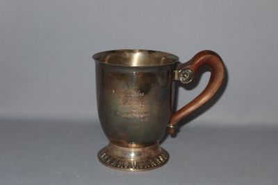 une tasse en argent avec un manche en bois posée sur une table