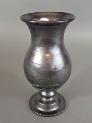 un vase en argent contenant une bougie, posé sur une table