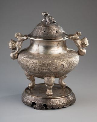 un vase en argent richement décoré, surmonté d'un oiseau