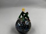 petite figurine en verre représentant une grenouille assise sur une balle