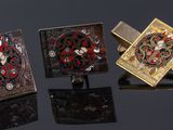 three cufflinks of different colors and designs on a black surface