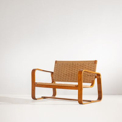 une image représentant une chaise en bois avec une assise tressée, posée sur une surface blanche