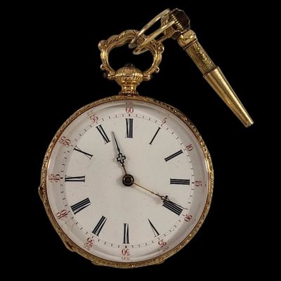 une montre de poche en or et un stylo sur fond noir