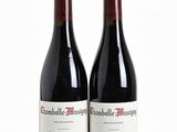 two bottles of red wine sitting next to each other on a white surface