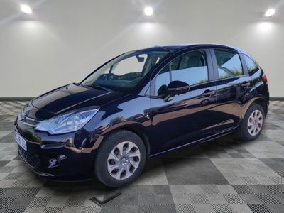 une voiture noire est garée dans une pièce au sol en damier