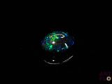a close up of a green and black glass ball on a black surface