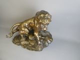 bronze statue of a lion on a rock with a white background