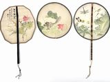 three chinese fan with designs of flowers and birds hanging on a wall
