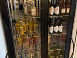 a man standing in front of a refrigerator filled with bottles of wine