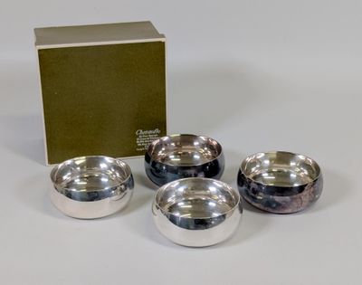 trois bols en argent et une boîte posés sur une surface blanche