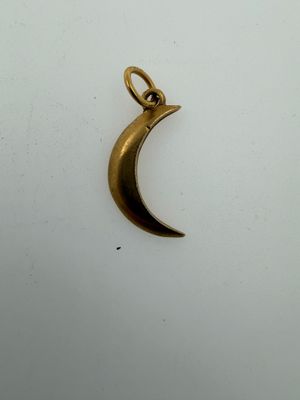 a close up of a gold crescent charm on a white surface