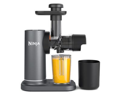 a close up of a juicer with a glass of orange juice