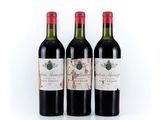 three bottles of wine are lined up on a white surface