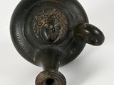 a black vase with a lion head on it
