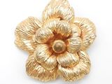 an image of a gold flower brooch on a white background
