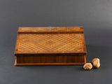 an old wooden box with two walnuts next to it on a gray surface