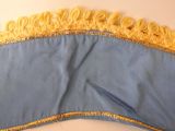 a close up of a blue and yellow dress with yellow fringes