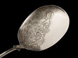 a silver spoon with a design on it on a black background