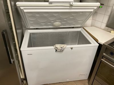 a white chest freezer in a kitchen next to a stove