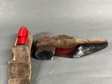 pair of brown sued shoes with red soles on a gray surface