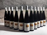 bottles of wine are lined up on a table in front of a stone wall