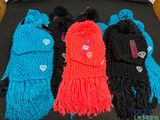 quatre écharpes tricotées de couleurs différentes sur un fond noir