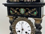 a black and gold clock on a stand on a white background