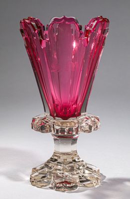 pink glass vase with a flower shaped base on a white surface