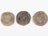 three silver and bronze coins, one of which has a face and the other of which is a head