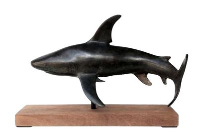 statue of a shark on a wooden base on a white background