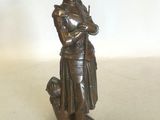 figurine en bronze représentant une femme tenant un chien, posée sur un socle