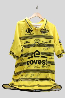 un gros plan sur un maillot de foot jaune suspendu à un cintre