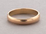 a close up of a gold wedding ring on a table