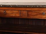 a wooden cabinet with a marble top in the corner of a room