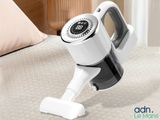 a white and black vacuum on a bed next to a pillow
