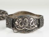 two silver bracelets with initials and scrolls on them