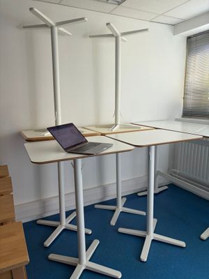un ordinateur portable posé sur un bureau, dans une pièce recouverte d'une moquette bleue