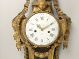a gold clock hanging on the wall next to a wall clock