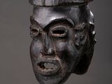 a wooden mask on a stand against a gray background