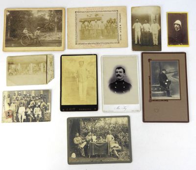 une vieille photo montrant un groupe d'hommes et de femmes assis sur une table