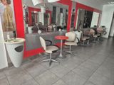 une photo d'un salon de coiffure avec des fauteuils et des miroirs