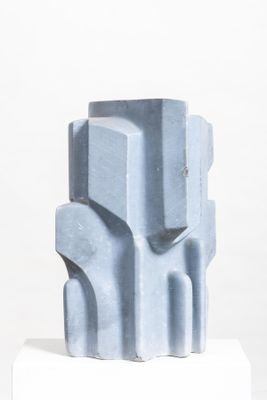 a blue sculpture on a white pedestal on a white surface