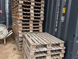 une pile de palettes en bois posée à côté d'un conteneur