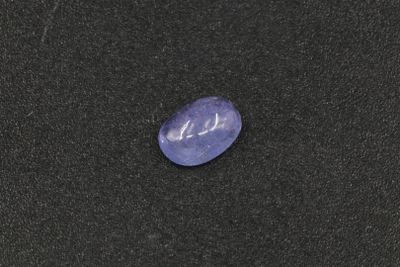 a purple stone on a black surface with a black background