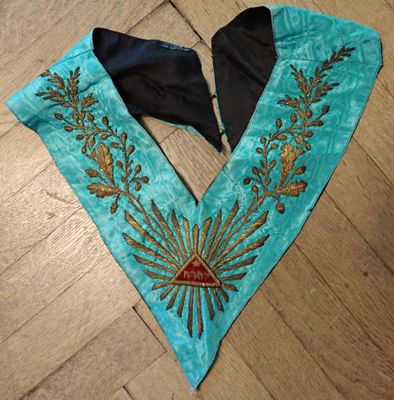 un gros plan sur un collier bleu et or posé sur un parquet