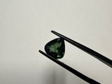 a close up of a pair of tongs holding a green tourmaline