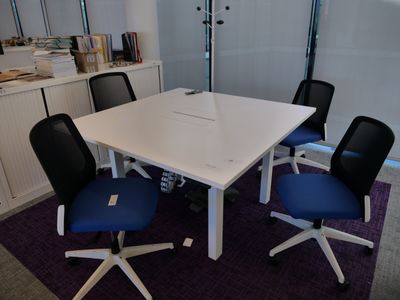 une table blanche avec des chaises bleues dans une pièce