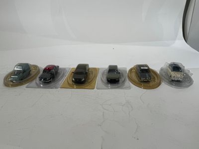 several toy cars are lined up in plastic bags on a white surface