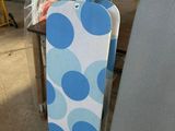 a blue and white polka dot ironing board and a blue and white ironing board on a table