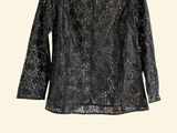 a black top with sequins on it hanging on a hanger